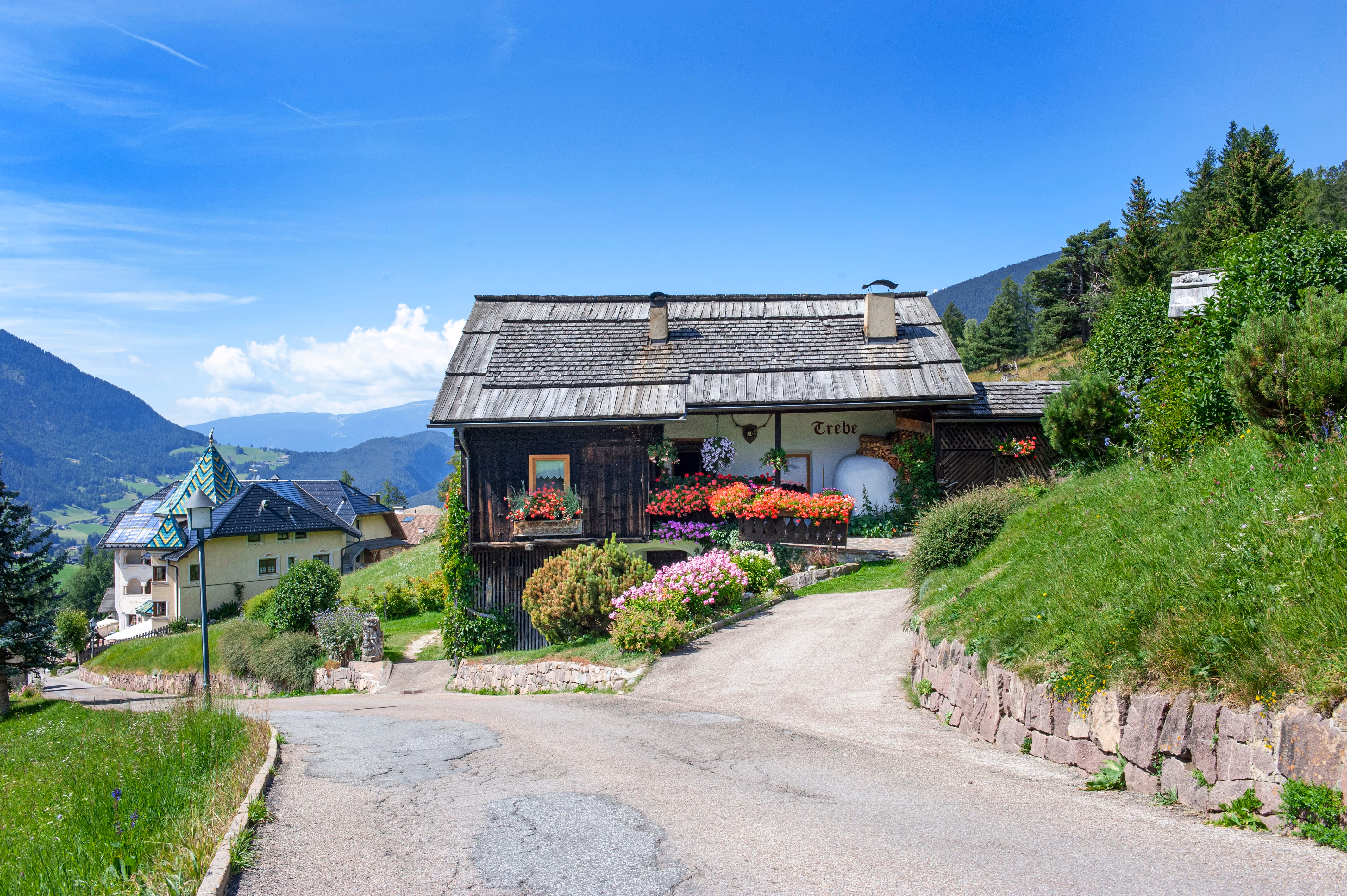Trebe on its hillside above the road, Sassolungo in the distance